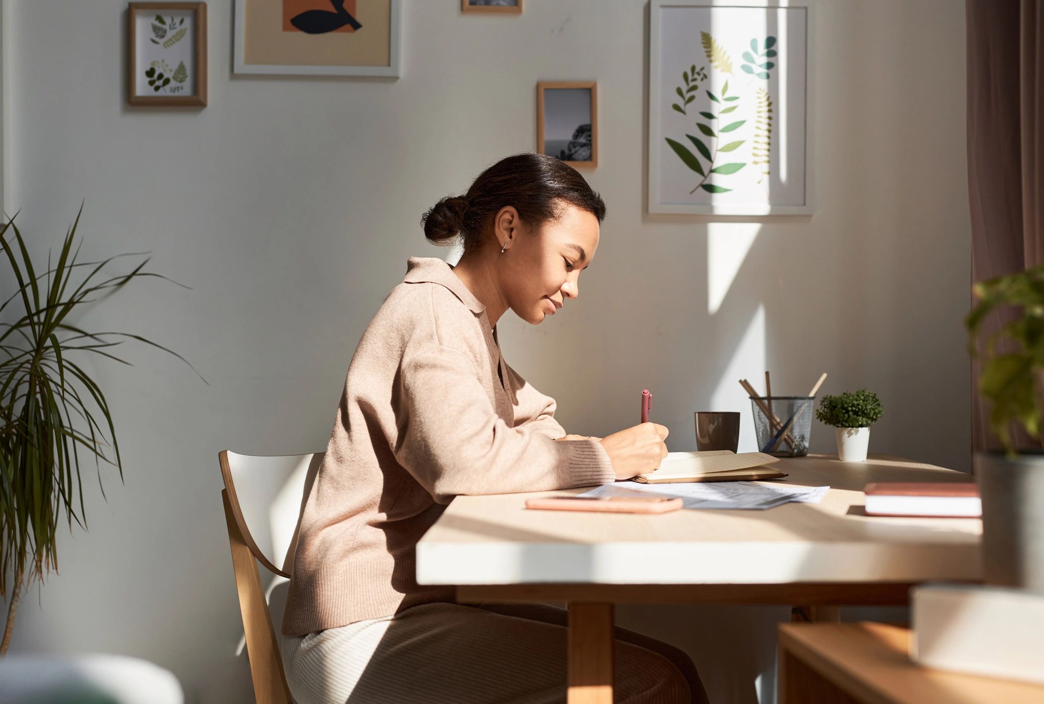 Woman writing in a notebook at home in soft light
