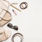 Female summer accessories and clothing items on light textured background with copy space