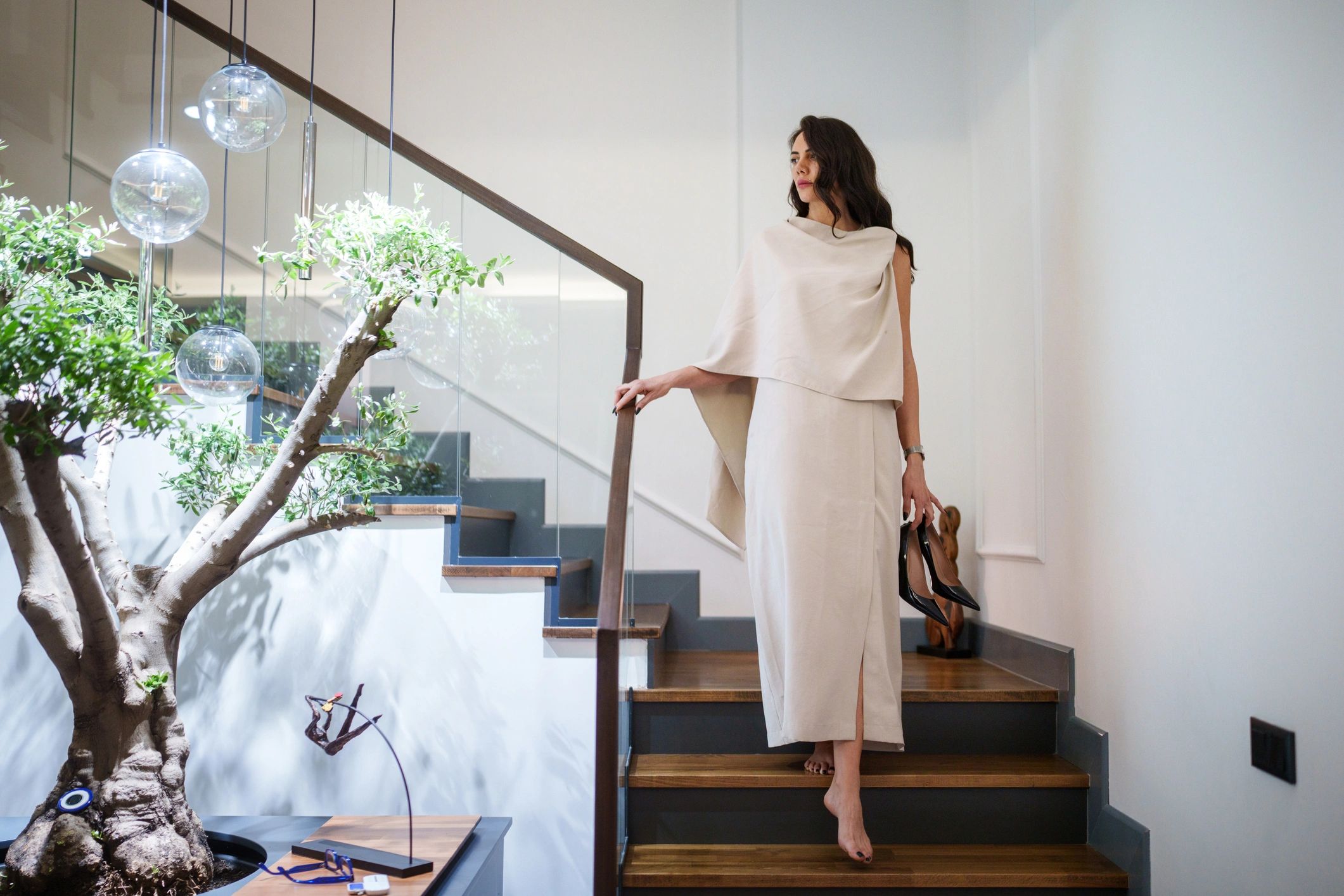 Woman holding heels at home near a staircase
