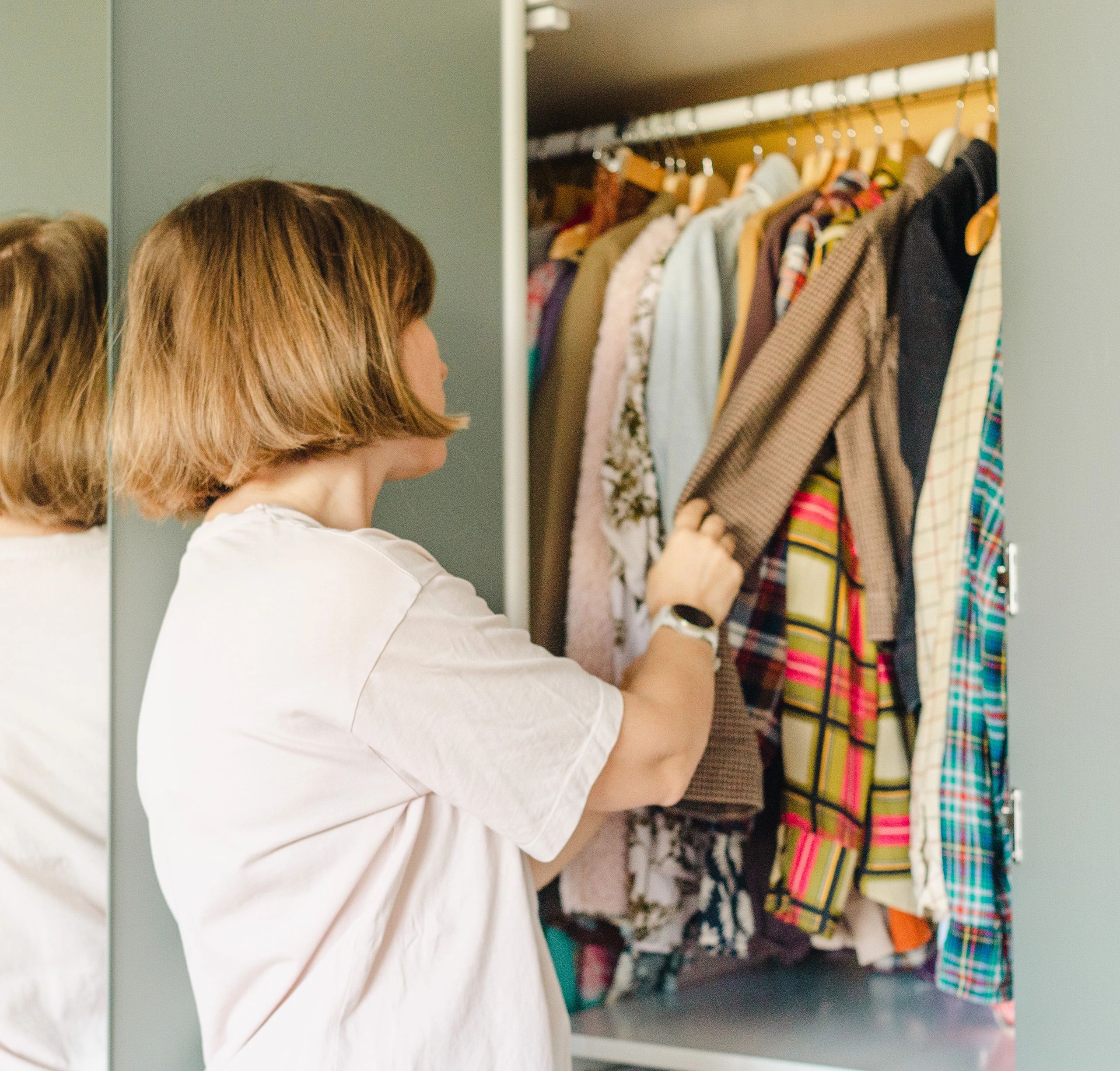 Woman organizing clothing in a closet, representing wardrobe systems