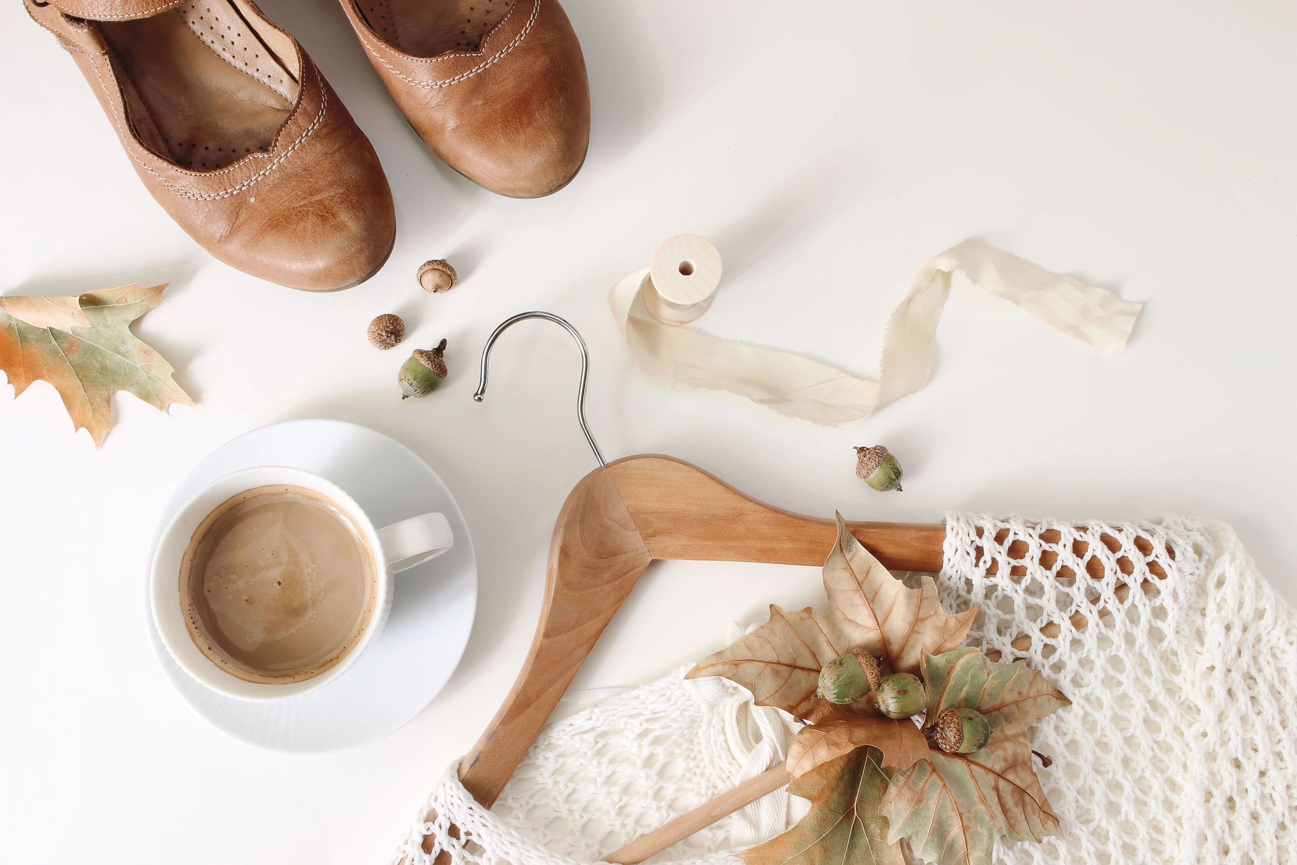 Flat lay of a neutral capsule wardrobe with sweater, shoes, and accessories